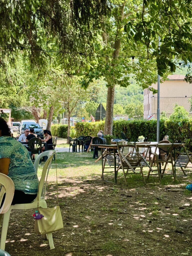 Terras onder de bomen in Cerreto di Spoleto waar locals genieten van porchetta en Italiaanse lunch in de schaduw