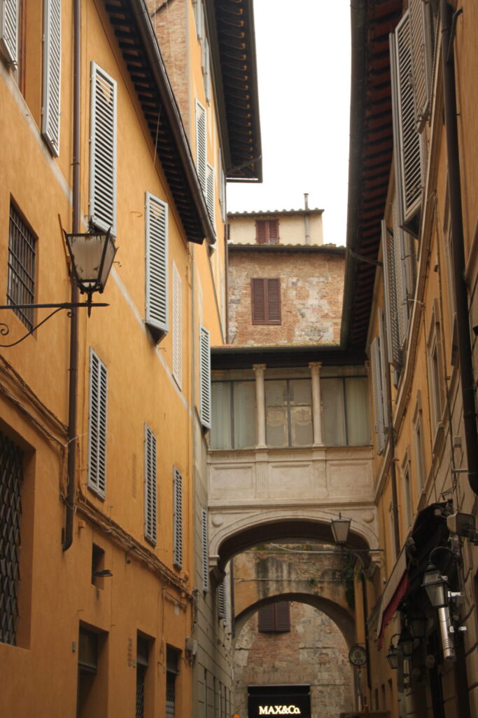 Typisch smal straatje met brug tussen historische gebouwen in het centrum van Siena in Toscane